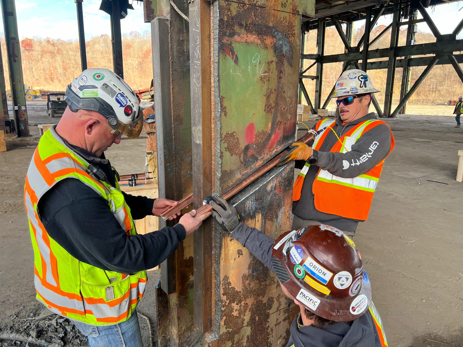 Three NADC team members preparing copper pipe salvaged during structural dismantling