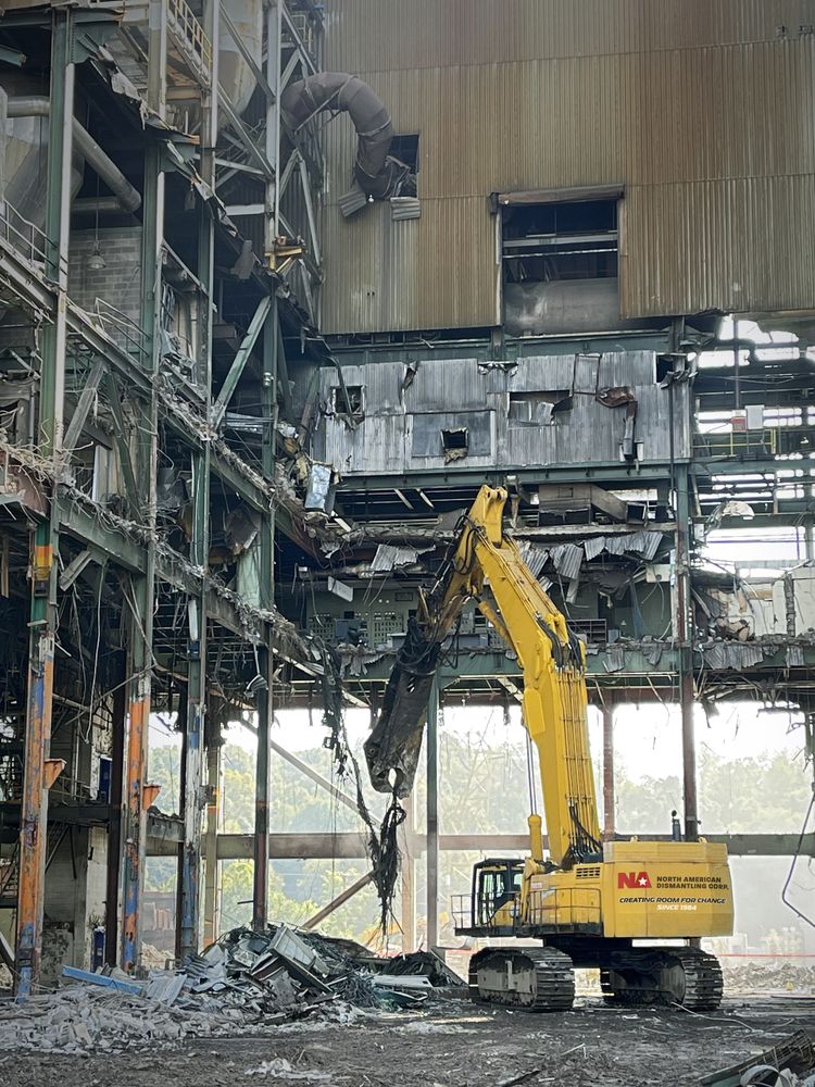 Excavator performing selective dismantling inside an industrial facility