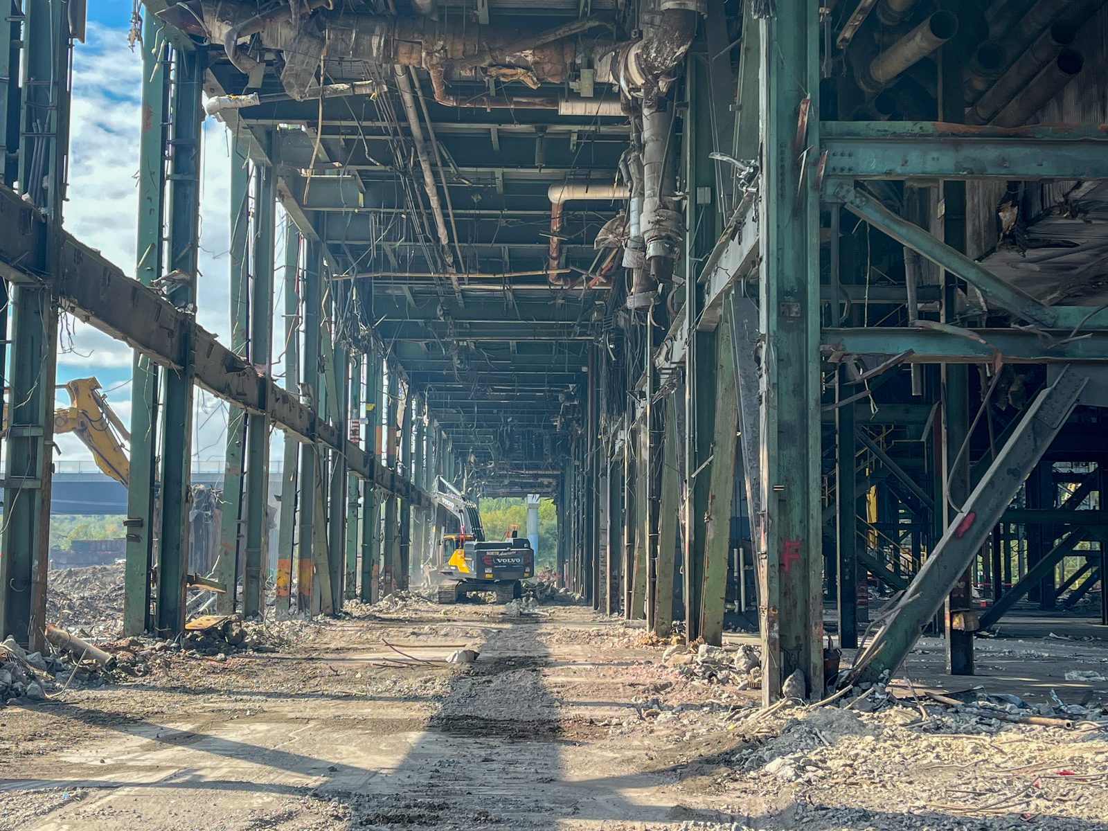 Excavator clearing debris inside the stripped steel frame of Hatfield Power Station