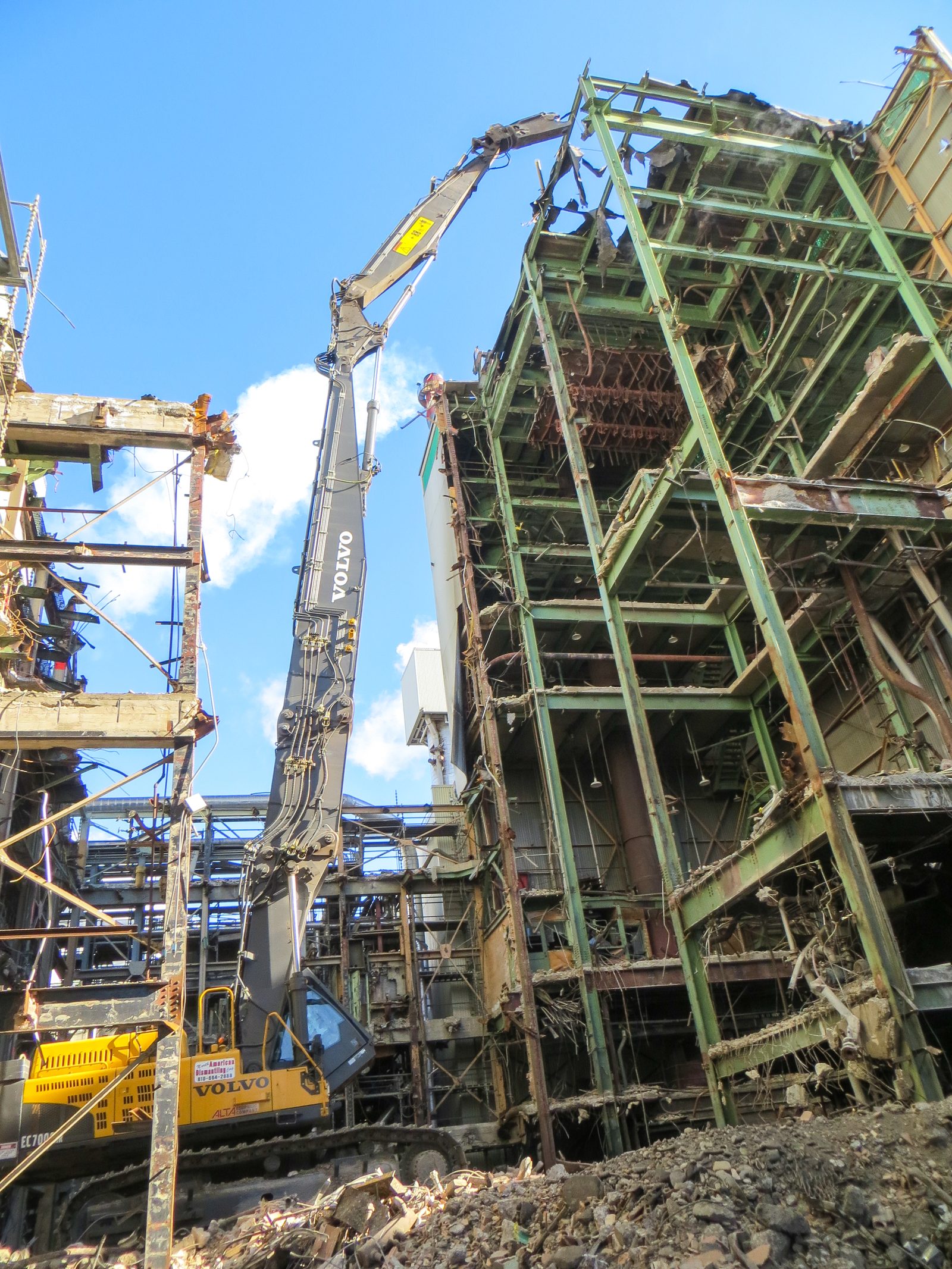 NADC high-reach excavator dismantling the steel frame of a recovery boiler building