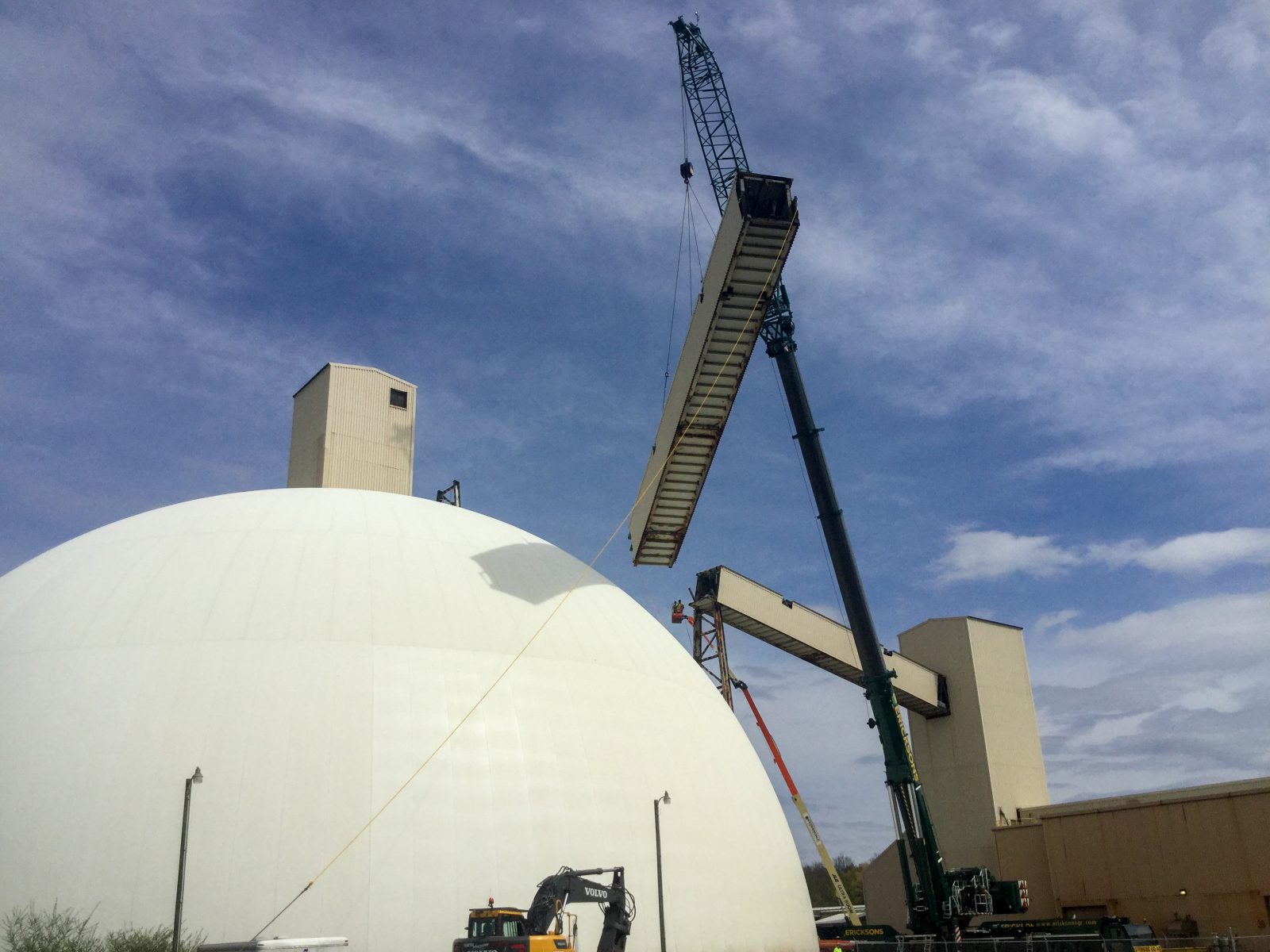 Crane pick lowering a section of the salt conveyor enclosure beside the storage dome