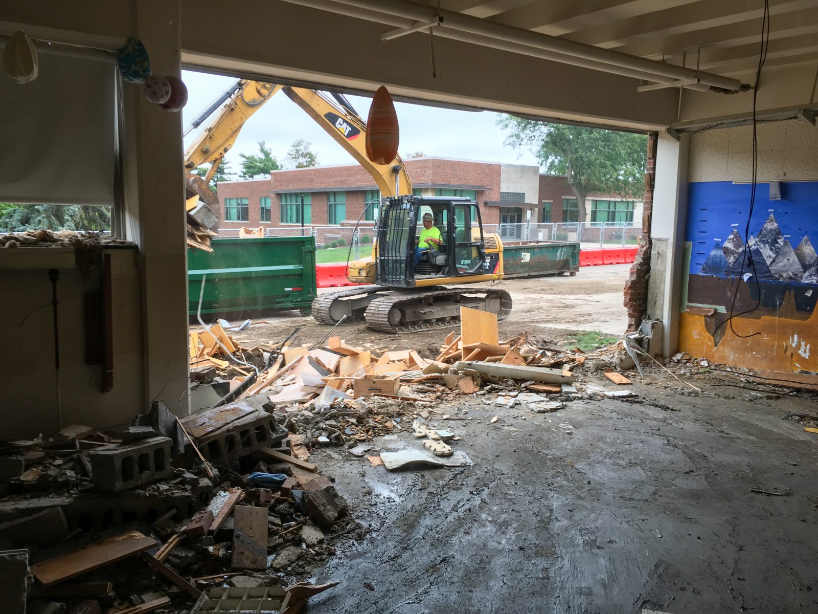Interior strip-out at Strong Hall with an excavator loading demolition debris through the wall opening