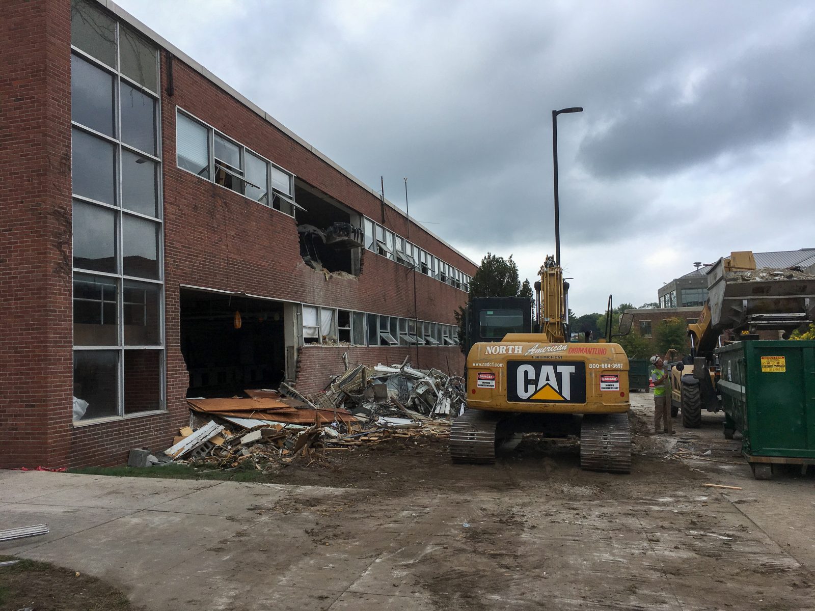 NADC excavator removing debris beside an opened exterior wall of Strong Hall at Eastern Michigan University
