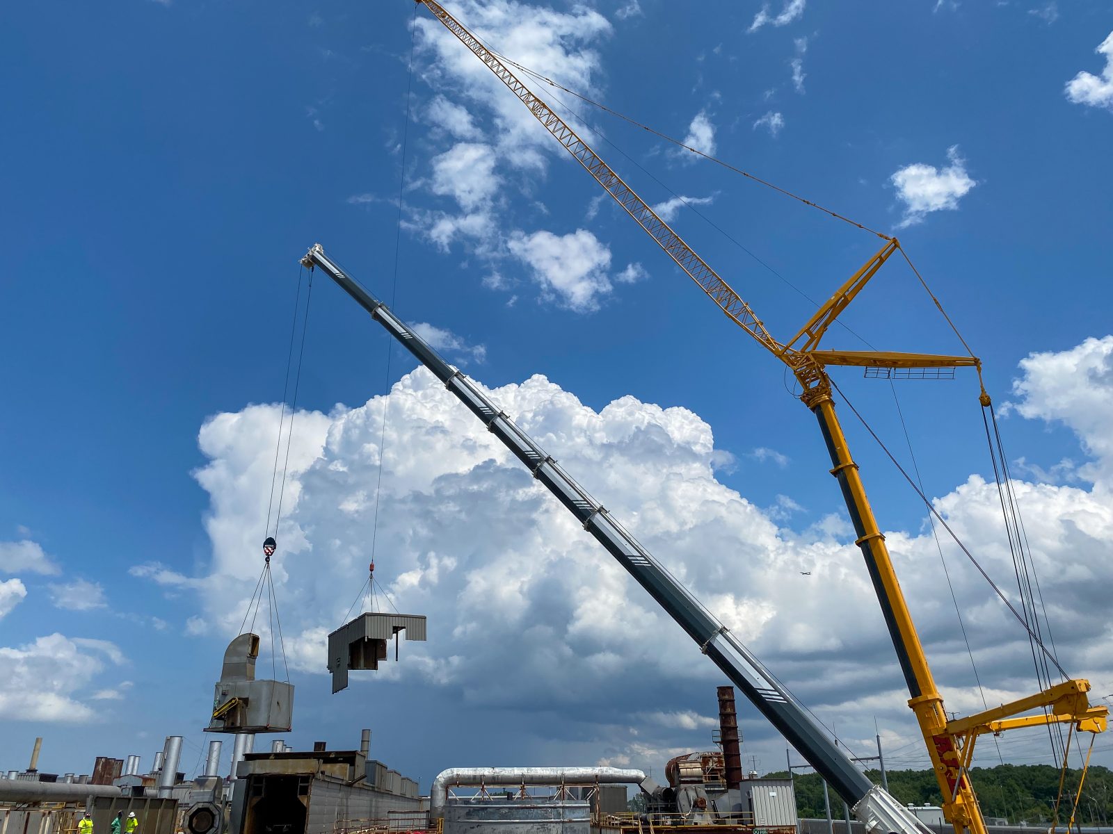 Cranes hoisting rooftop oven and duct components from the plant roof to grade