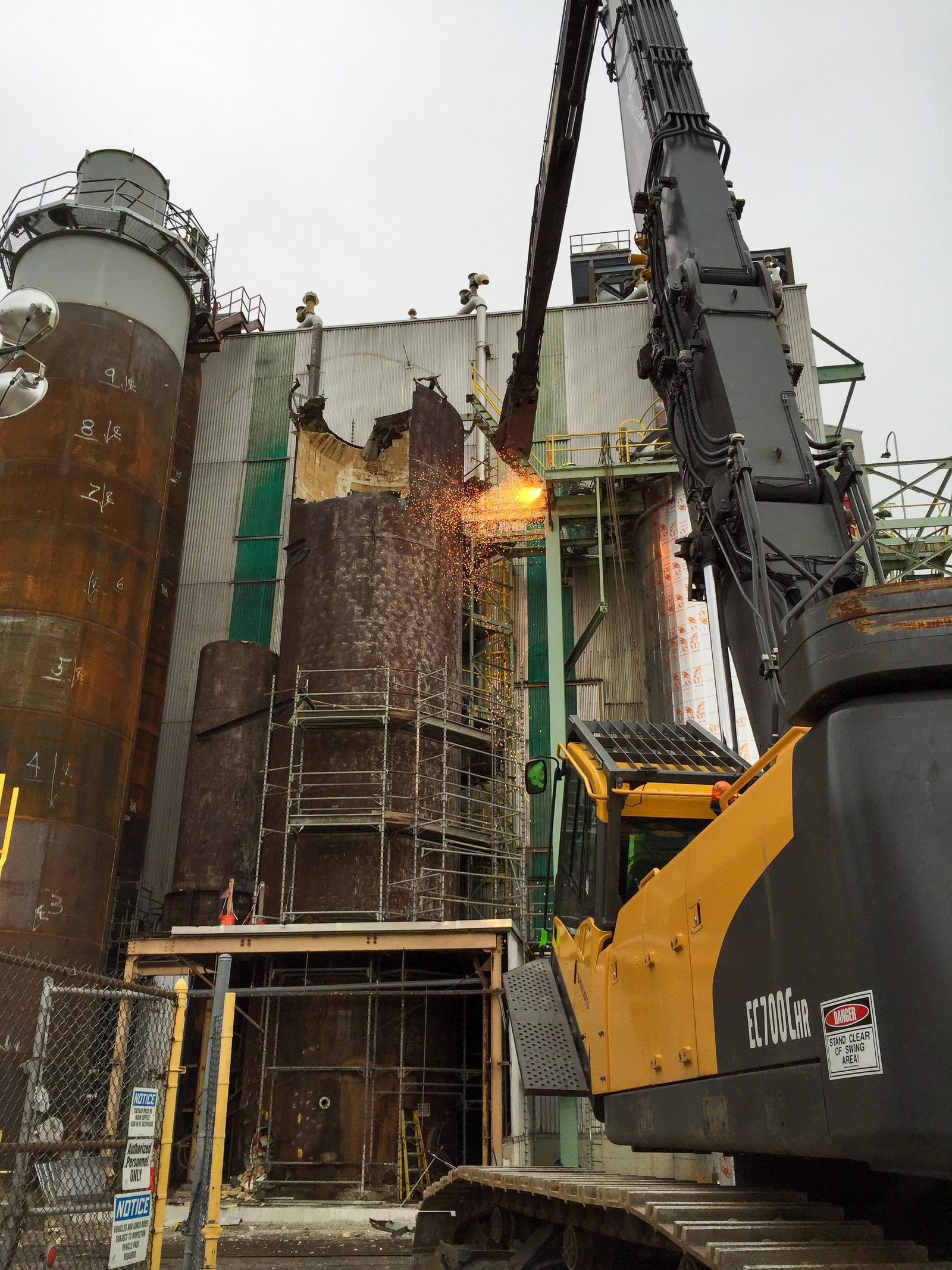 Excavator working in tight clearances beside operating structures at the Glatfelter mill