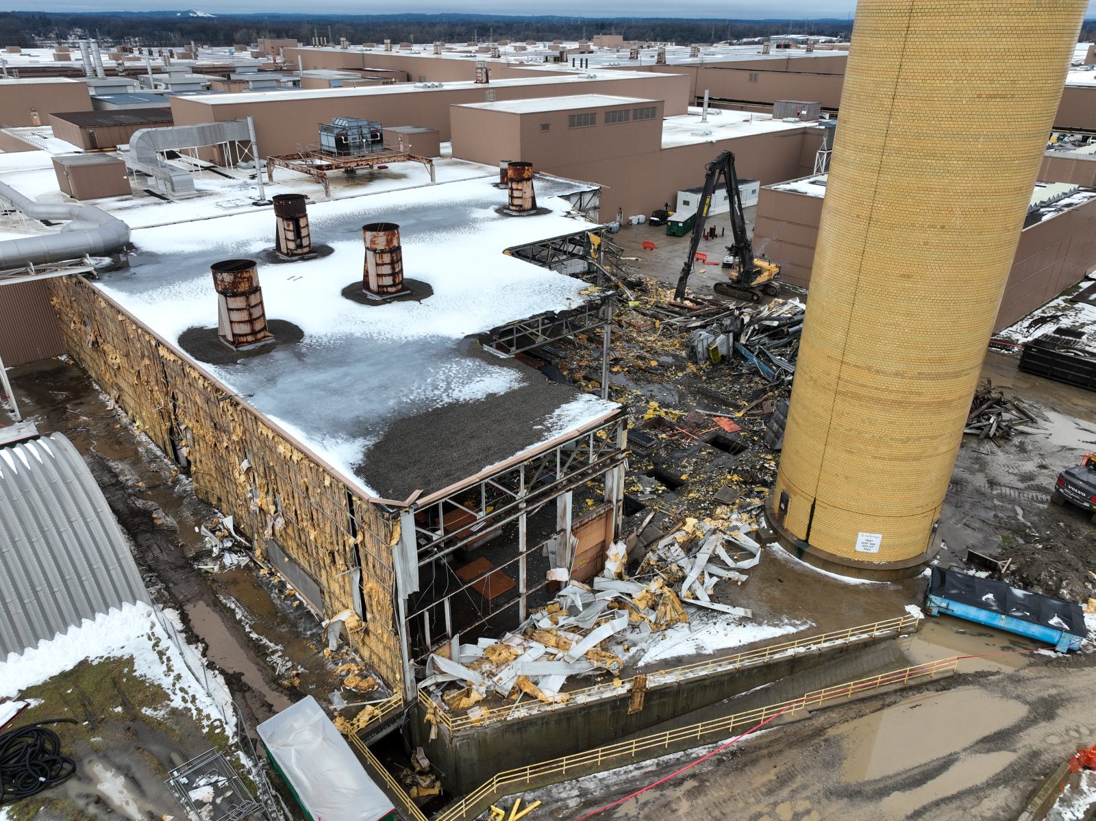 Aerial view of NADC demolishing an exterior process building beside the brick exhaust stack at the Lake Orion plant