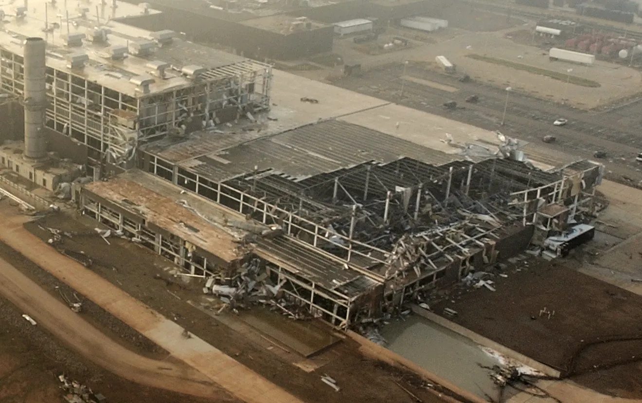 Aerial view of collapsed roof framing and storm damage across the assembly plant before demolition