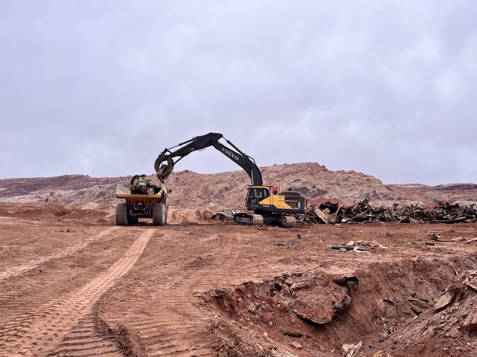 NADC excavator and haul truck separating scrap metal from a soil and demolition debris stockpile