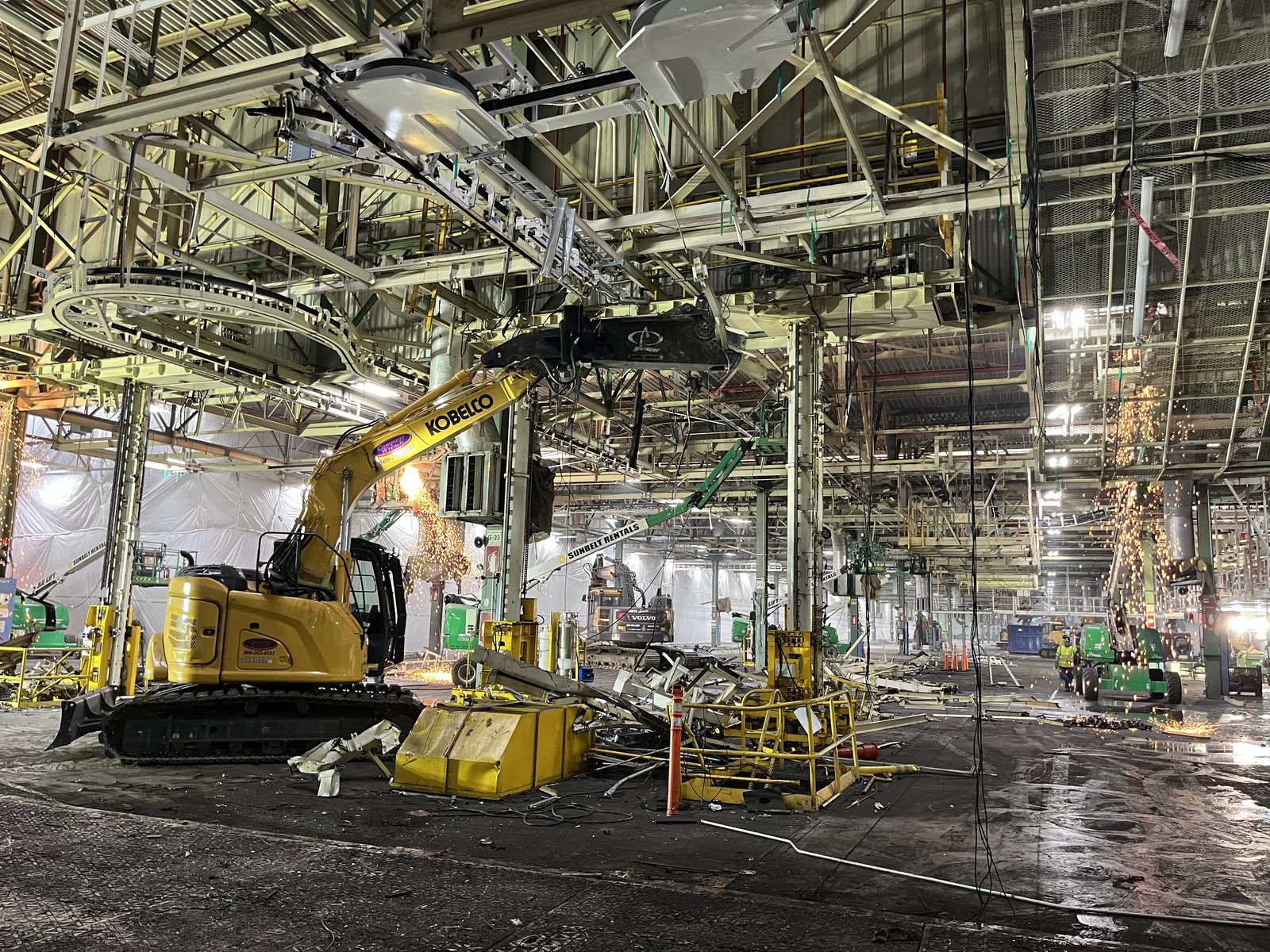 NADC excavator removing overhead process equipment inside an active industrial building