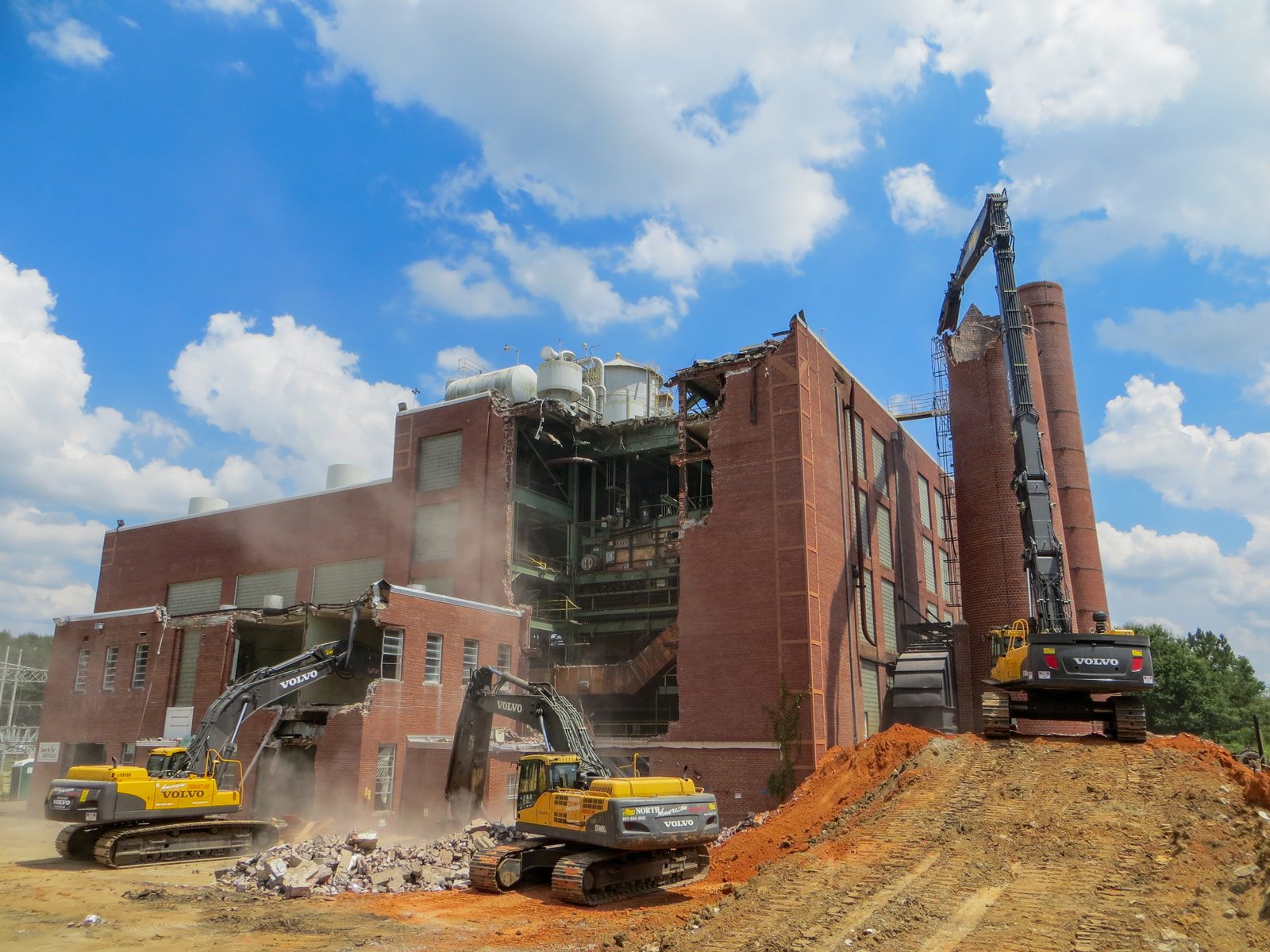 Three NADC high-reach excavators taking down a brick power plant building and its stack
